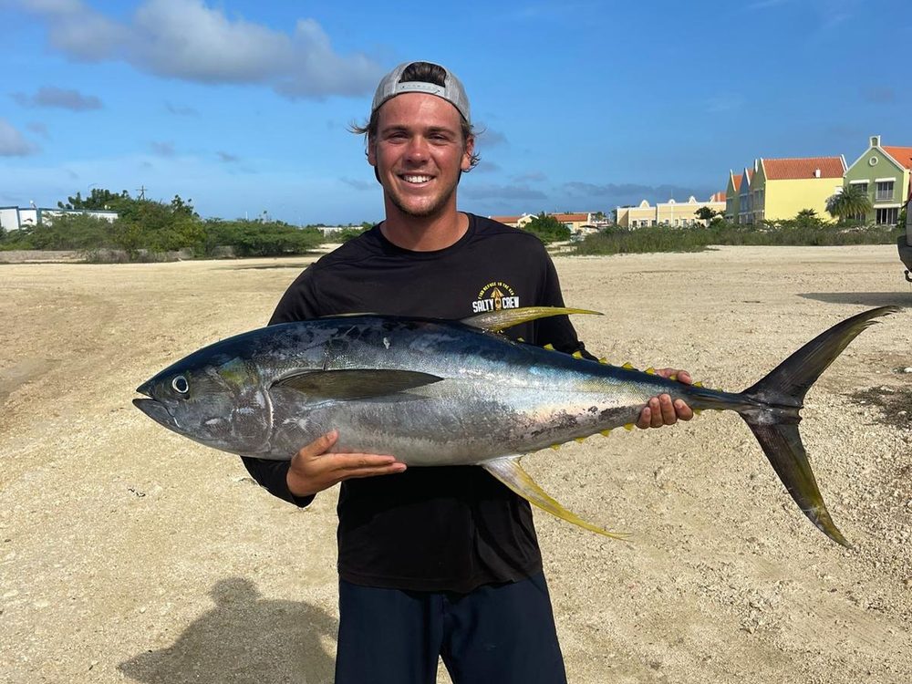 Visser met een grote geelvintonijn op het strand van Bonaire